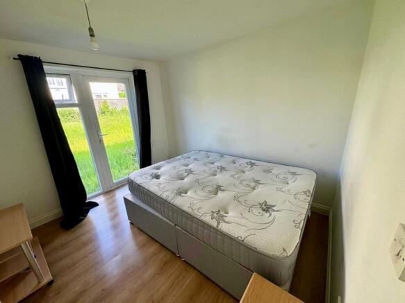 A bright double bedroom featuring a large windo...