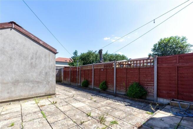A bright and sunny paved garden area with well-...