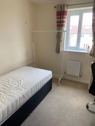 A bright single bedroom featuring a comfortable...
