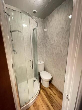 A compact modern bathroom featuring a curved gl...