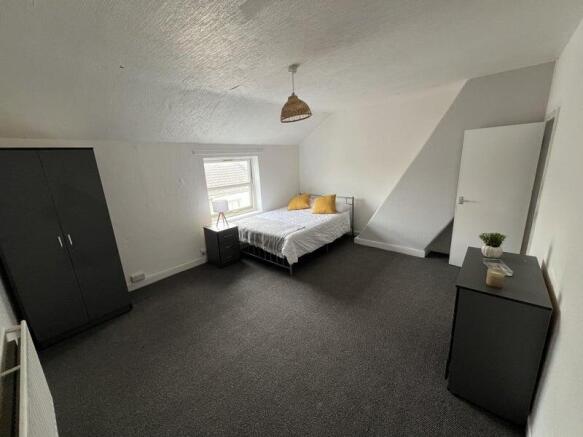 A spacious double bedroom featuring a neatly ma...
