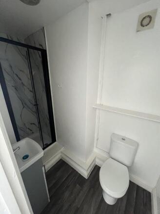 A compact, modern bathroom featuring a white to...
