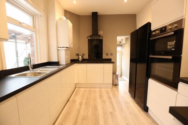 A modern kitchen with sleek white cabinets, bla...