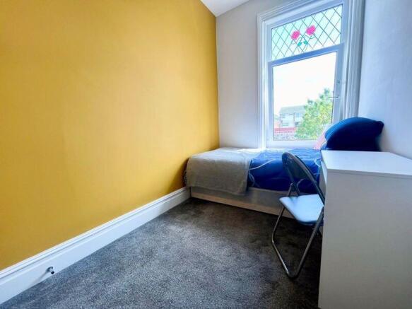 A bright and cozy single bedroom featuring a co...