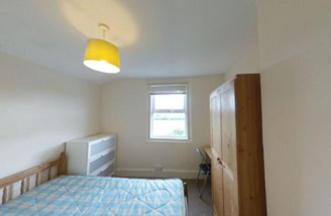 A cozy double bedroom featuring a wooden bed fr...