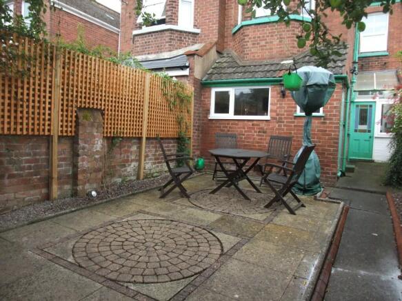 Charming paved garden area featuring a neat woo...