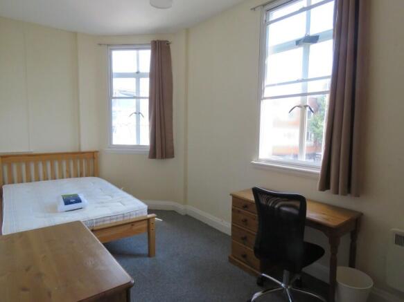 A bright single bedroom featuring two large win...