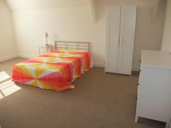 A spacious double bedroom featuring a bright wi...