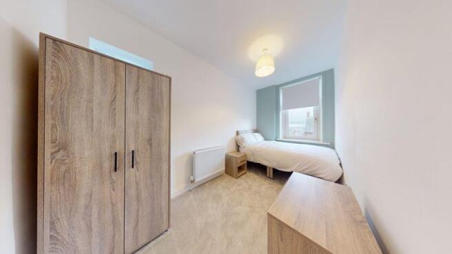 A neat and cozy single bedroom featuring a ward...