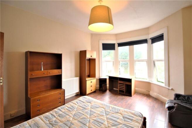 A spacious master bedroom featuring a large bay...