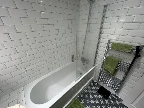 Modern bathroom featuring a clean white tiled b...