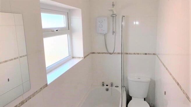 Bright and clean bathroom featuring a bathtub a...