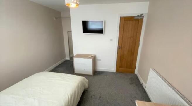 A neat and tidy single bedroom featuring a comf...