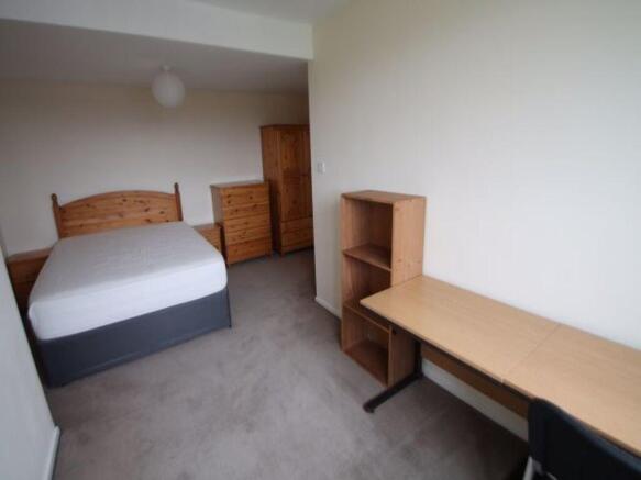 A tidy and functional bedroom featuring a comfo...