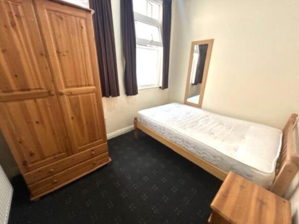 A tidy single bedroom featuring a wooden bed fr...