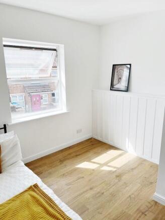 Bright, freshly painted bedroom with warm wood ...