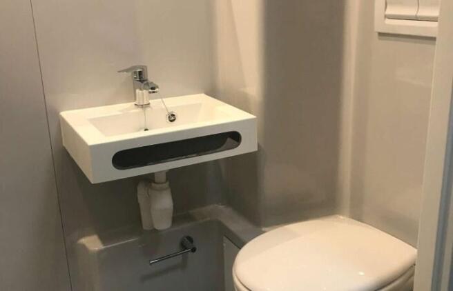Compact and modern single toilet featuring a wa...