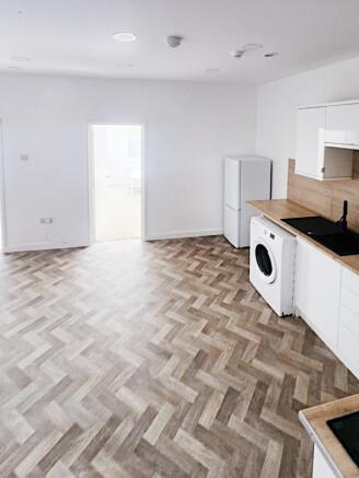 Bright open-plan kitchen area with modern white...