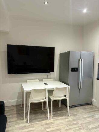 A modern kitchen area featuring a large flat-sc...
