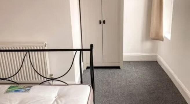 A neat and tidy single bedroom featuring a meta...