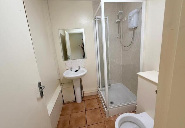 A compact bathroom featuring a shower enclosure...