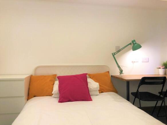 A cozy and tidy single bedroom featuring a whit...