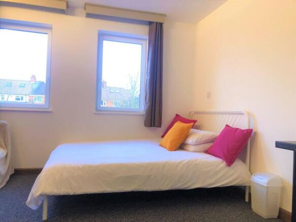 A cozy single bedroom with a neatly made bed ad...