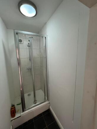 A compact bathroom featuring a glass-enclosed s...