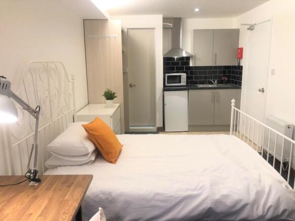 A cozy single bedroom featuring a neat white me...