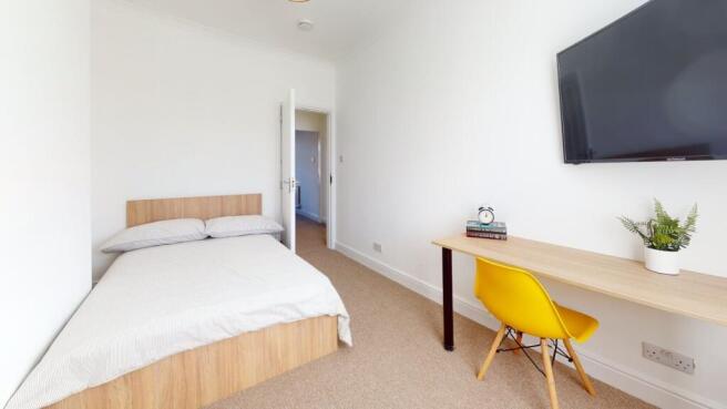 A tidy and bright bedroom featuring a comfortab...
