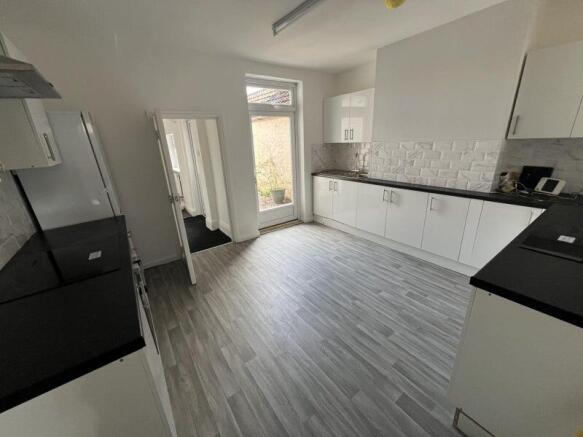 A spacious, modern kitchen with sleek white cab...