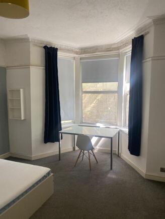A bright and airy bedroom featuring a large bay...