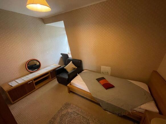 A cozy single bedroom featuring a neatly made b...