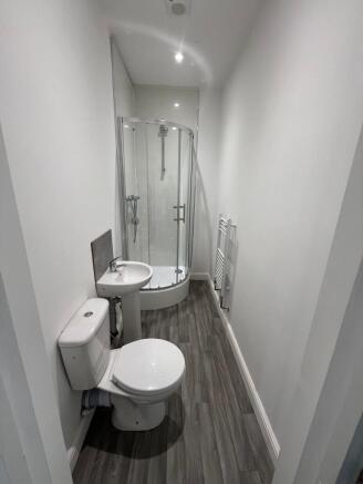 A modern bathroom featuring a curved glass show...