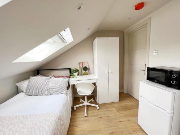 Bright and cozy single bedroom featuring a skyl...