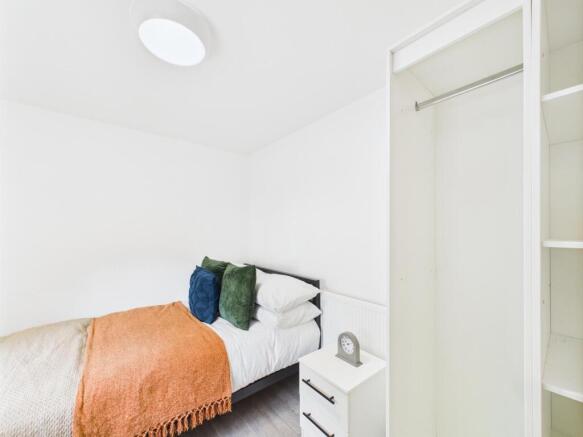 A cozy single bedroom featuring a neatly made b...