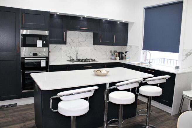 Modern kitchen featuring sleek dark cabinetry w...