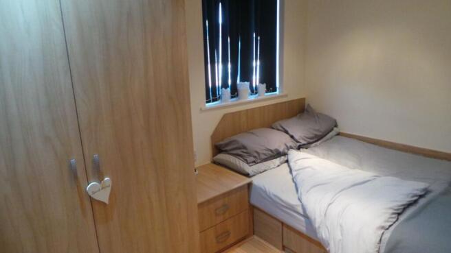 A cozy double bedroom with neutral bedding, a w...