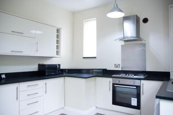 Modern kitchen with sleek white cabinets, black...