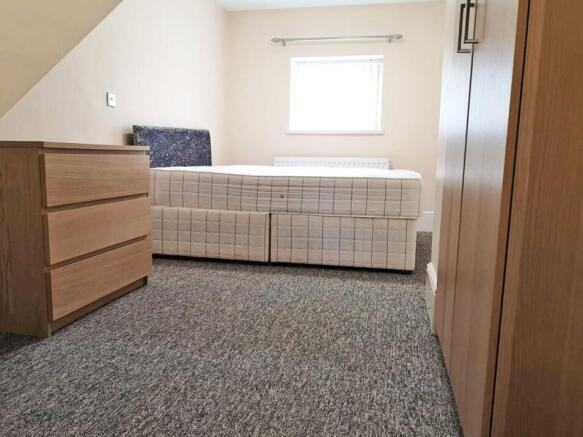 A neat and tidy single bedroom featuring a comf...