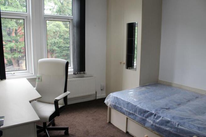 A bright and tidy bedroom featuring a large win...