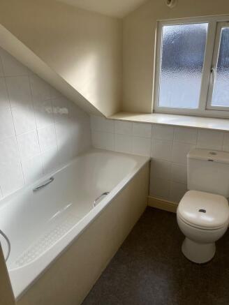 A clean and bright bathroom with a bathtub, whi...