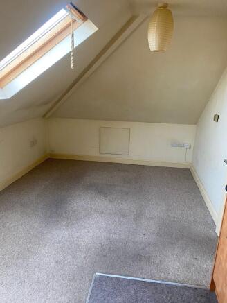 A cozy bedroom with a sloped ceiling, featuring...