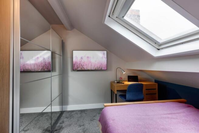 A cozy and well-lit bedroom with a sloped ceili...