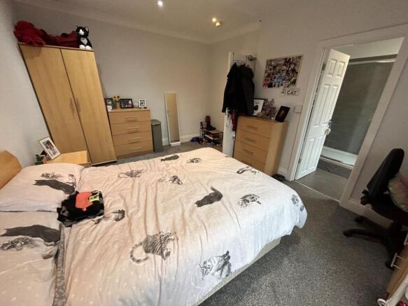 A well-lit bedroom featuring a large bed, wardr...