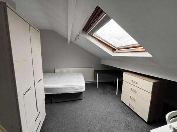 A bright and tidy bedroom with a skylight windo...