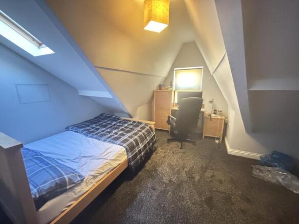 A cozy single bedroom with a neatly made bed, a...