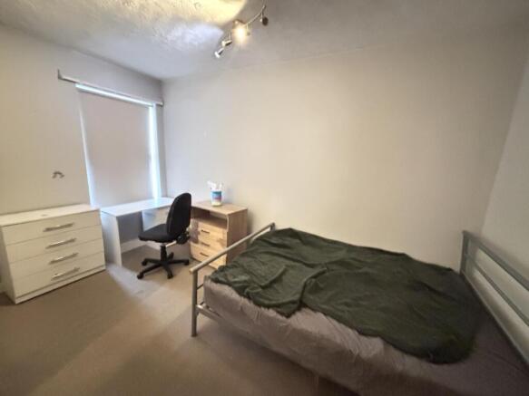 A neat and cozy bedroom featuring a bed with si...