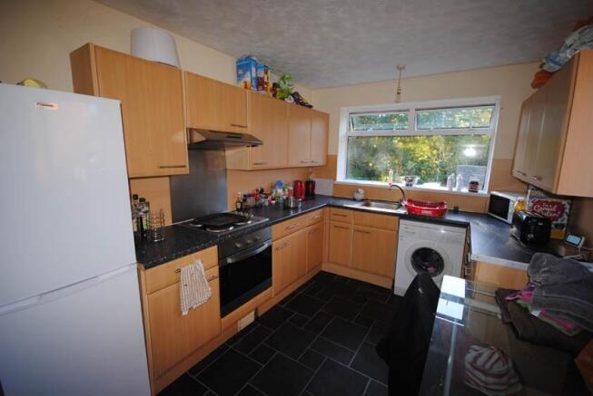 A well-lit kitchen featuring wooden cabinetry, ...