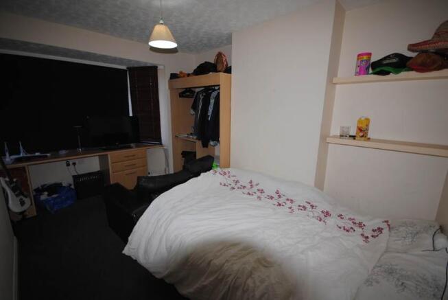 A bright and cozy bedroom featuring a neatly ma...